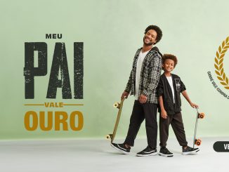 Anúncio da promoção "Meu Pai Vale Ouro" das Lojas Humanitarian. Um homem sorridente rodeado de moedas de ouro segura um bilhete de raspadinha. O texto diz: "Pai meu raspou, achou, ganhou! Vale-Ouro. Ganhe vale-compra de até 50 reais na hora ou um botton."