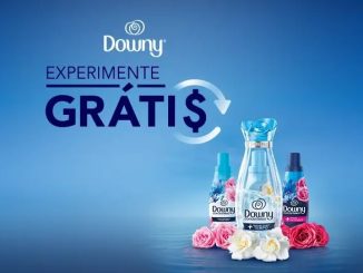 Imagem promocional da Downy com frascos de amaciante e flores em tons de rosa e azul sobre um fundo azul claro. O texto "Experimente Grátis" destaca a oferta de reembolso para a compra de produtos da marca.