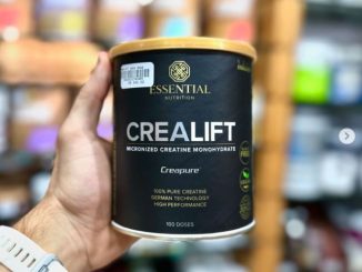 Uma mão segura um pote de suplemento CREALIFT da Essential Nutrition. A embalagem é preta com detalhes dourados, destacando que o produto é uma creatina monohidratada micronizada de alta performance, com tecnologia alemã. O rótulo informa que contém 100 doses e é 100% pura.