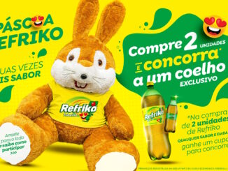 Publicidade da Páscoa Refriko apresentando um coelho de pelúcia grande usando camiseta amarela da marca ao lado de garrafas de Tubaína sobre fundo amarelo e detalhes verdes.