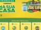 Banner promocional da Consigaz com fundo amarelo e detalhes em verde. No topo esquerdo, o logo da empresa e o título Na Sua Casa em letras grandes. À direita, um botijão de gás azul e uma TV mostrando um casal comemorando com o texto Concorra a 200 TVs Aiwa. Na base, quatro passos explicam como participar: compre, receba, cadastre-se e concorra.