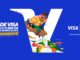 Anúncio publicitário da Visa para a Copa do Mundo da FIFA com fundo azul. No centro, uma letra V branca estilizada serve de moldura para a ilustração colorida de um jogador de futebol em movimento. À esquerda, o texto diz Vai de Visa e viva o clima da Copa do Mundo da FIFA sem perrengue. À direita, aparecem os logotipos da Visa e da Copa do Mundo com a frase Parceiro Mundial.