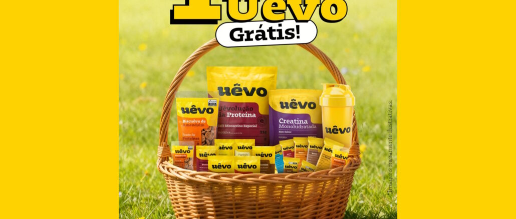 Uma cesta de vime cheia de produtos da marca Uêvo, como suplementos e barras de proteína, posicionada sobre um gramado verde ensolarado para anunciar a promoção de um ano de produtos grátis.
