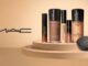 Logotipo da MAC à esquerda e diversos produtos de maquiagem para o rosto das linhas Studio Radiance e Studio Fix dispostos sobre uma plataforma circular bege.