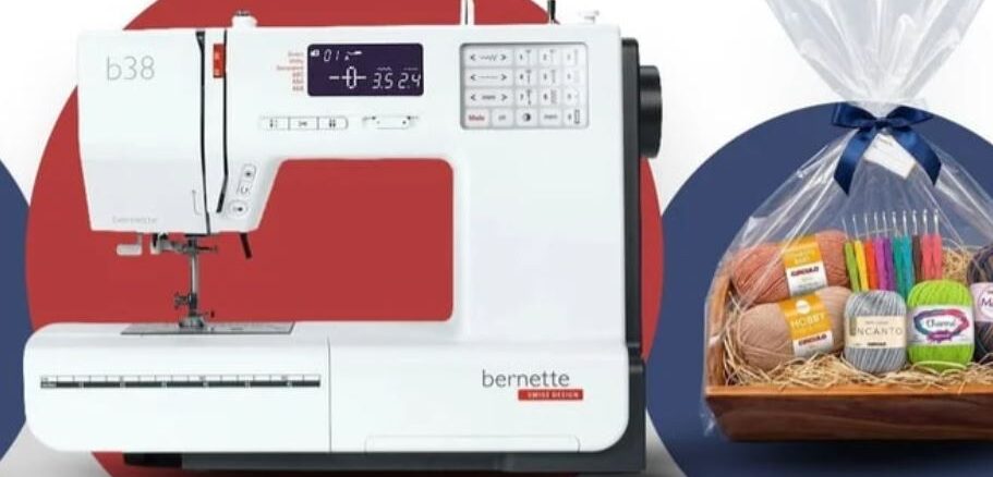 Máquina de costura branca modelo Bernette b38 ao lado de uma cesta de presente com novelos de linha e agulhas de crochê coloridas.