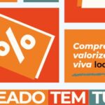 Design gráfico promocional com blocos de cores em laranja, vermelho e azul. A imagem contém a ilustração de uma etiqueta de preço com símbolo de porcentagem e os textos Compre local, valorize local, viva local e Lajeado tem tudo.