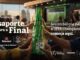 Várias mãos seguram garrafas de vidro verde da cerveja Heineken agrupadas no centro da imagem em um gesto de celebração. O fundo mostra um ambiente de lounge com vista para a cidade e uma tela transmitindo uma partida de futebol, acompanhado de textos sobre a promoção da UEFA Champions League.