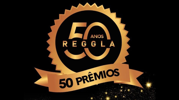 Selo comemorativo dourado dos 50 anos da Reggla com anúncio de 50 prêmios sobre fundo preto com brilhos.