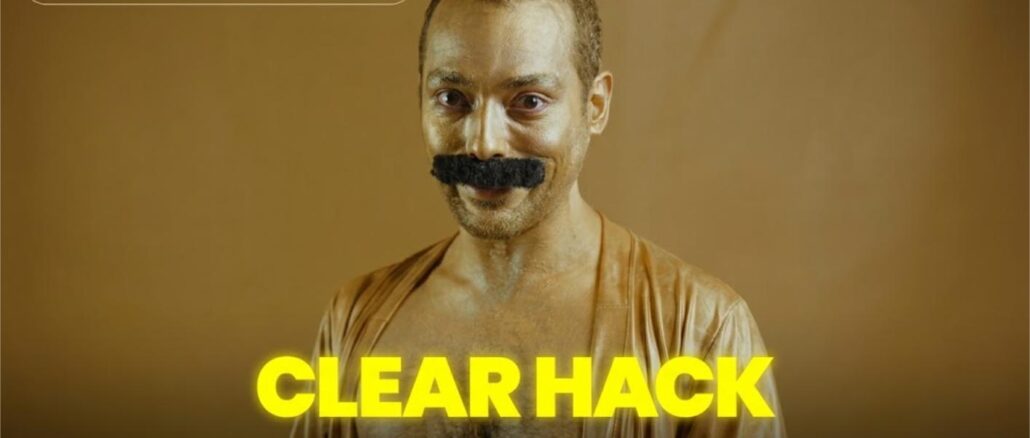 Concurso #ClearHack no Tiktok Homem com bigode falso e rosto coberto de sujeira olha para a câmera com expressão sorridente. Na parte inferior da imagem, os textos em amarelo "CLEAR HACK" e "Concorra ingressos pra Copa e 20 mil reais!" se destacam sobre fundo dourado.