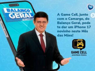 Homem de terno escuro com os braços abertos posicionado à frente de um smartphone gigante com o logotipo do Balanço Geral. Fundo azul decorado com corações e logotipo da Game Cell.