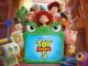 Personagens animados de Toy Story 5, incluindo Woody, Buzz Lightyear, Jessie e outros brinquedos, reunidos ao redor de um tablet infantil com capa de sapo, exibindo o logotipo do filme.