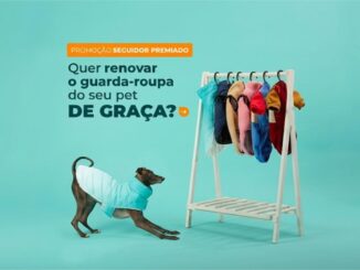 Cachorro de pelagem escura vestindo um colete azul claro se alonga em direção a uma arara de madeira com diversas roupas coloridas para animais em um fundo azul turquesa.