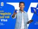 Homem negro sorridente segurando um cartão de crédito Visa e uma máquina de cartões sobre um fundo azul com elementos da marca e da Copa do Mundo da FIFA.