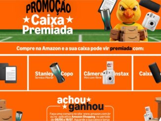 Banner promocional da Amazon com fundo laranja anunciando a promoção Caixa Premiada. A imagem destaca um mascote em formato de ave segurando caixas, além dos prêmios Kindle 11ª geração, copo térmico Stanley, câmera Instax Mini com filme e caixa de som portátil.