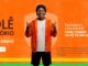 Peça publicitária em fundo laranja promovendo a campanha “Rolê Aleatório”, com um homem sorridente (ex-jogador de futebol, Ronaldinho Gaúcho) ao centro vestindo jaqueta laranja, camiseta branca, bermuda preta e gorro escuro, fazendo gestos com as mãos. À esquerda aparece o nome da promoção e um botão de cadastro. À direita há o texto informando o sorteio de três vales-viagem de R$30 mil cada.