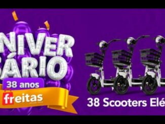 Banner roxo de aniversário de 38 anos das Lojas Freitas com balões roxos, faixa dourada e três scooters elétricas brancas com cesto frontal