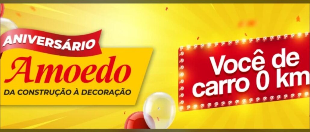 Banner amarelo e vermelho da promoção Aniversário Amoedo Você de Carro Novo 2026, com faixa vermelha escrito Aniversário Amoedo da Construção à Decoração e letreiro luminoso vermelho com a frase Você de carro 0km, decorado com confetes e balões vermelho e branco