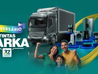 Banner de aniversário de 37 anos da Tintas Darka, em fundo verde-azulado, com caminhão de entrega e diversos eletrodomésticos como geladeira, micro-ondas, lava-e-seca, cafeteira e aspirador robô dispostos em pedestais iluminados, além de uma família formada por pai, mãe e filho sorrindo e comemorando com os punhos erguidos.