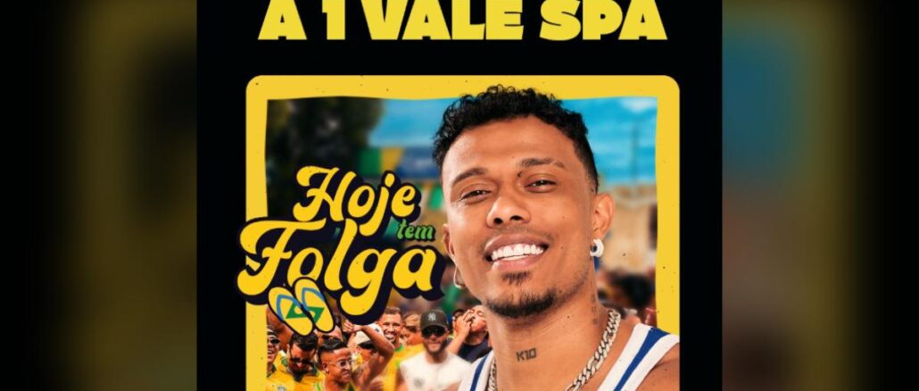 Homem sorridente com corrente e brinco posa em frente a arte da campanha Hoje Tem Folga do K10, com fundo de torcedores em festa de verde e amarelo e texto anunciando sorteio de vale spa