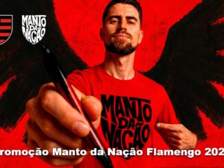 Homem com barba veste camiseta vermelha escrita Manto da Nação, aponta caneta para a câmera, com escudo do Flamengo e logo Manto da Nação ao fundo vermelho com asas negras