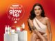 Banner da promoção Repara no Glow Up Dove, com selo circular branco escrito Promoção Repara no Glow Up Dove sobre fundo gradiente laranja e vermelho, exibindo à direita uma mulher de cabelos longos e cacheados castanho-escuros sentada, usando um top branco assimétrico, com tatuagens no braço, e à esquerda produtos Dove das linhas Pele e Cabelo dispostos sobre pedestais cilíndricos claros.