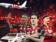 Roleta Premiada Fla-Prêmios 2026 reúne três jogadores do Flamengo com uniforme oficial ao centro, ao lado de avião temático do clube, moletom preto com estampa "Flamengo", carro elétrico infantil personalizado nas cores rubro-negras e fundo com luzes vermelhas e douradas remetendo ao Maracanã à noite.