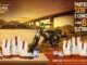 Imagem promocional da Vista Linda Cafés Especiais mostrando produtos da marca dispostos ao lado de uma bike elétrica, com o mar, uma ponte e o pôr do sol ao fundo, anunciando sorteio de bikes elétricas nas Lojas Perim.