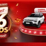 Banner da promoção de aniversário de 26 anos da Rede Smart Supermercados, com carro Citroën C3 0km e motos 0km expostos em um palco iluminado, sobre fundo vermelho festivo.