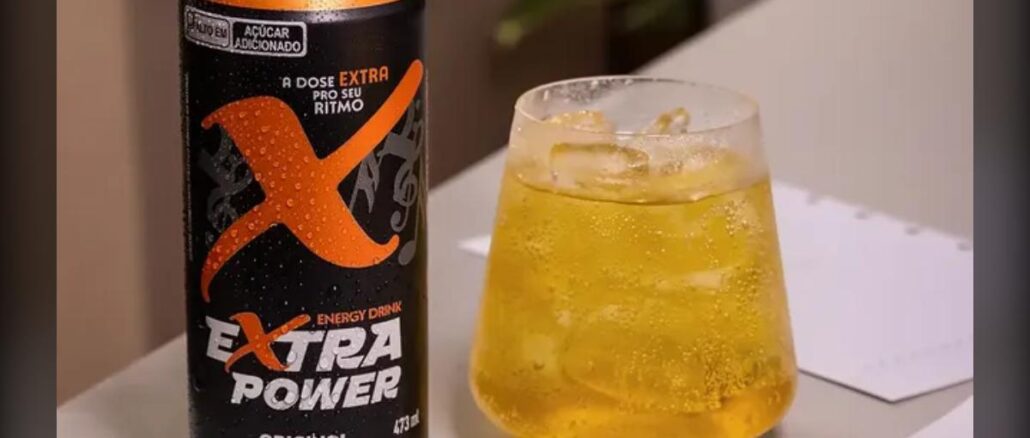 Lata de energy drink Extra Power Original 473ml ao lado de um copo com gelo e bebida amarelada, sobre superfície clara.