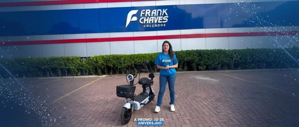 Promoção de Aniversário Frank Chaves Calçados: apresentadora ao lado de uma moto elétrica sorteada na campanha comemorativa de 44 anos da rede.