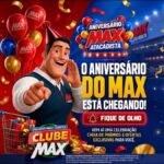 Banner do Aniversário Max Atacadista com mascote sorridente de colete azul apontando para frente, carrinho com presentes, balões vermelhos, azuis e dourados, fachada da loja ao fundo e o anúncio de que o aniversário do Max está chegando, exclusivo para clientes Clube Max.