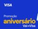 Banner da Promoção Aniversário Vai de Visa 2026, com fundo azul e jovem segurando caixas e sacolas coloridas.