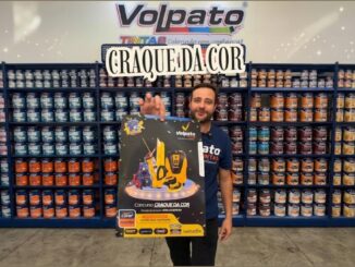 Funcionário da Volpato Tintas segura cartaz do Concurso Craque da Cor em loja de Maringá, Paraná