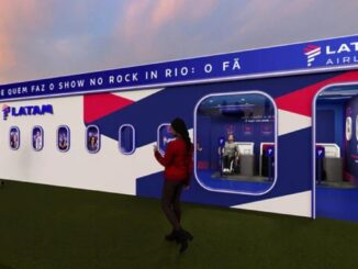 Estande da LATAM Airlines no Rock in Rio 2026, decorado com visual de fuselagem de avião nas cores azul, vermelho e branco, com a frase "A companhia aérea oficial de quem faz o show no Rock in Rio: O Fã" e logo LATAM Airlines no topo.