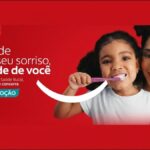 Promoção Colgate Cuide do Seu Sorriso, Cuide de Você — menina escovando os dentes ao lado de mulher sorridente, em fundo vermelho com logotipo Colgate.