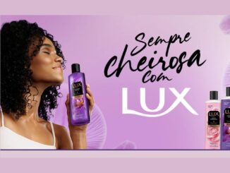 Banner da promoção Sempre Cheirosa com Lux, com mulher de cabelos cacheados segurando um sabonete líquido Lux Orquídea Negra e cinco frascos da linha Lux ao lado, com selo indicando que Lux Líquido dobra as chances no sorteio.