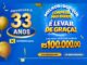 Banner azul da promoção de aniversário de 33 anos do X Supermercados, com balões dourados, a frase "Melhor do que comprar mais barato é levar de graça!" e o destaque para o prêmio final de R$100.000,00.