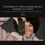 Mulher sorridente de cabelo black power segura um celular com o aplicativo do C6 Bank aberto, sob o título Portabilidade em Dobro: participe da nova campanha do C6 Bank.