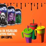 Cinco latas de Fanta de 350 ml com personagens de terror ao lado de três copos coloridos com alça e canudo, sobre fundo laranja, com o texto: na compra de R$20,00 em produtos Fanta, ganhe um copo.