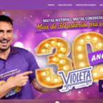 Homem sorridente com camisa roxa aponta para o número 30 dourado com lâmpadas e o logotipo dos Supermercados Violeta, ao lado do texto "Mais de 30 prêmios pra você!".