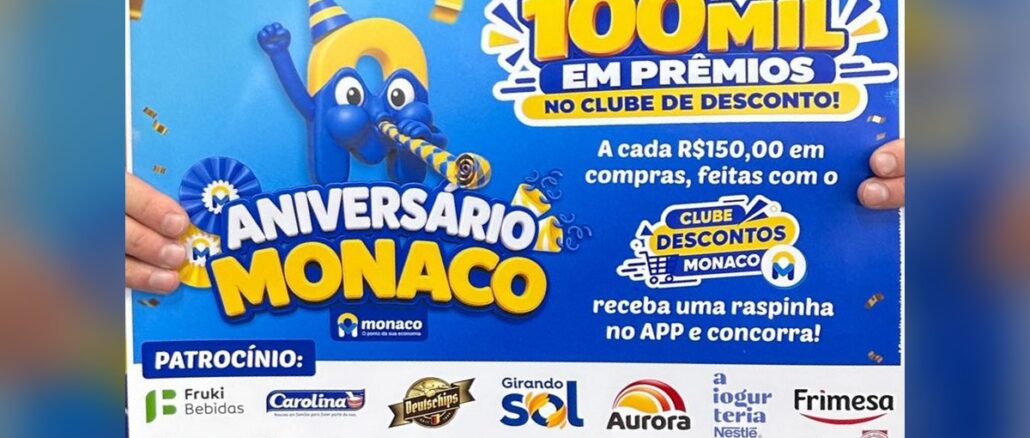 Cartaz da promoção Aniversário Monaco, do Monaco Atacado, com mascote azul em forma de letra M usando chapéu de festa e o anúncio de 100 mil em prêmios no Clube de Desconto, com logos dos patrocinadores no rodapé.