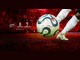 Bola de futebol branca e azul com a marca Cumbre sendo chutada por um jogador de meiões brancos, em um estádio lotado iluminado em vermelho, ao lado dos logotipos da Coca-Cola, da Conmebol Libertadores e da Conmebol Sudamericana.