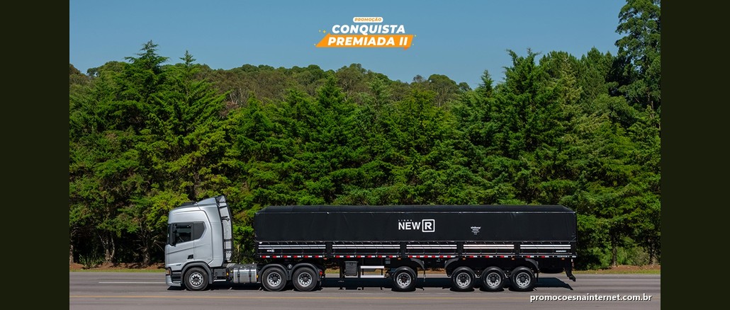 Caminhão prata com semirreboque graneleiro preto da Linha New R diante de uma mata verde, sob o selo "Promoção Conquista Premiada II".