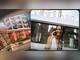 Mulher sorridente fala ao celular em frente à fachada com o letreiro Vanguard, ao lado de cartões com fotos de prédios residenciais e barra de busca com a frase "Onde tudo se conecta", arte da promoção 20 Anos Vanguard.