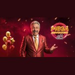 Homem sorridente de cabelos grisalhos e bigode, com terno vermelho brilhante e gravata dourada, ao lado do logotipo neon "Mega Aniversário Bom Parceiro", com balões dourados e vermelhos ao fundo.