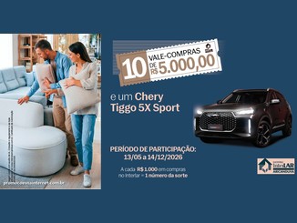 Casal sorridente abraçado a almofadas em loja de móveis, ao lado do anúncio da Campanha Interlar Aricanduva 2026: 10 vale-compras de R$5.000,00 e um Chery Tiggo 5X Sport, com participação de 13/05 a 14/12/2026.