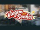 Logotipo da campanha Viagem dos Sonhos, em letras brancas com contorno vermelho, avião amarelo e trajeto pontilhado, sobre fundo desfocado de cidade.