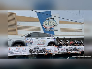 Carreta de aniversário do ZABCÊ Supermercados com um Chevrolet Tracker prata e motos sobre a plataforma, em frente à fachada do Grupo ABC, com faixa do Show de Prêmios 41 Anos