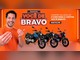 Arte da Promoção Você de Bravo da Avelloz com homem sorridente de camiseta laranja, letreiro em neon com o nome da promoção e três motos AZ170 Bravo nas cores azul, preta e vermelha sobre fundo laranja.